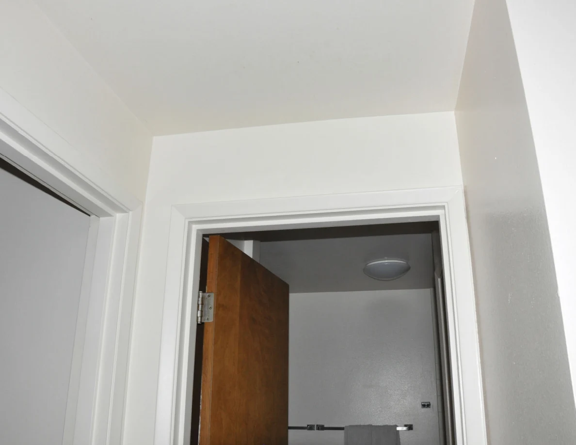 Upper bathroom doorway and ceiling above an open wooden door.