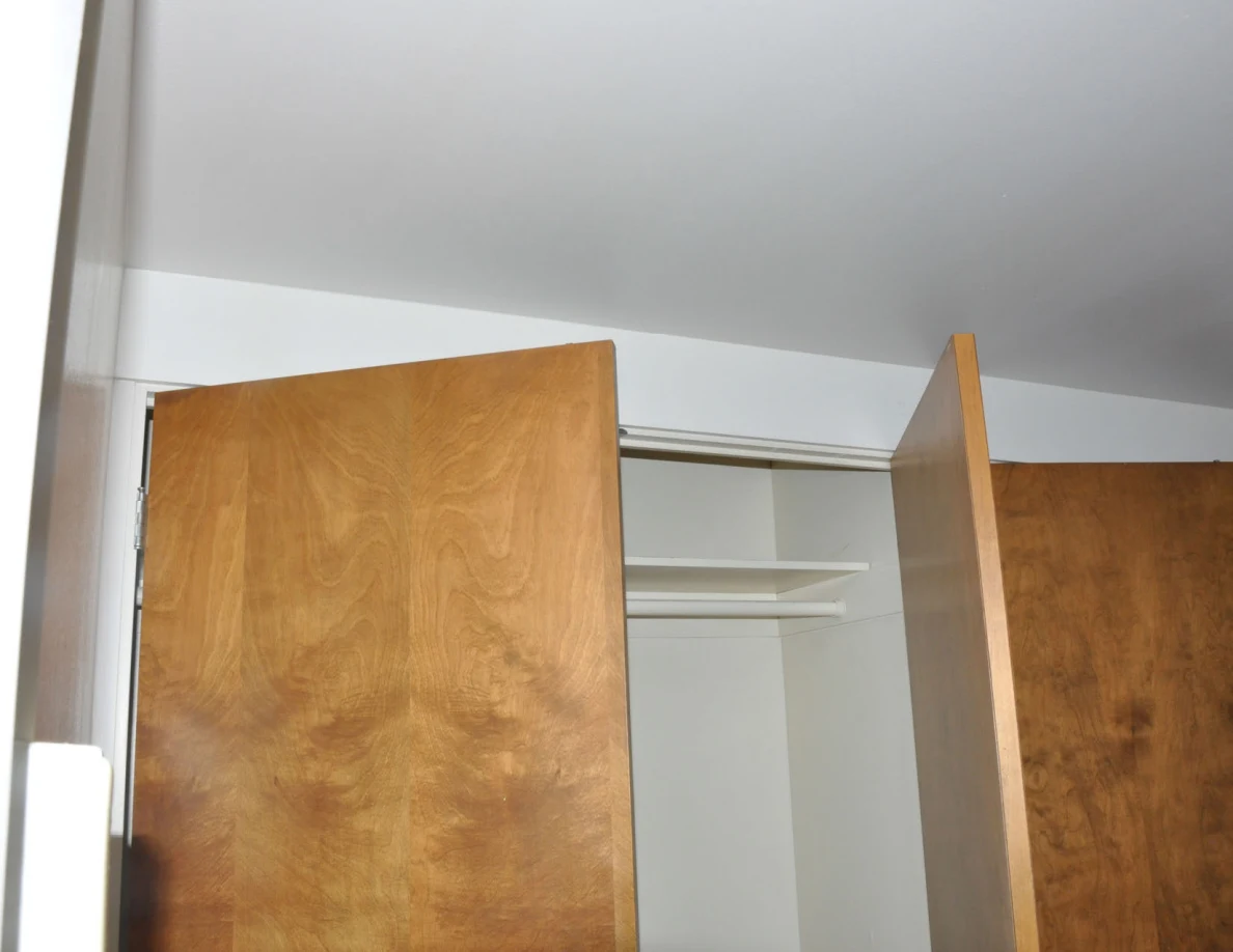 Upper closet doors and empty hanging rail beneath a plain ceiling.