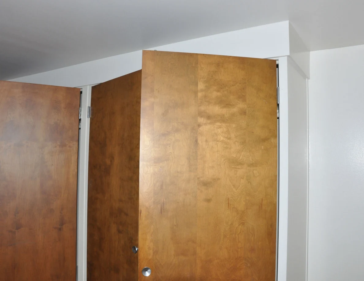 Upper sections of several open wooden closet doors.