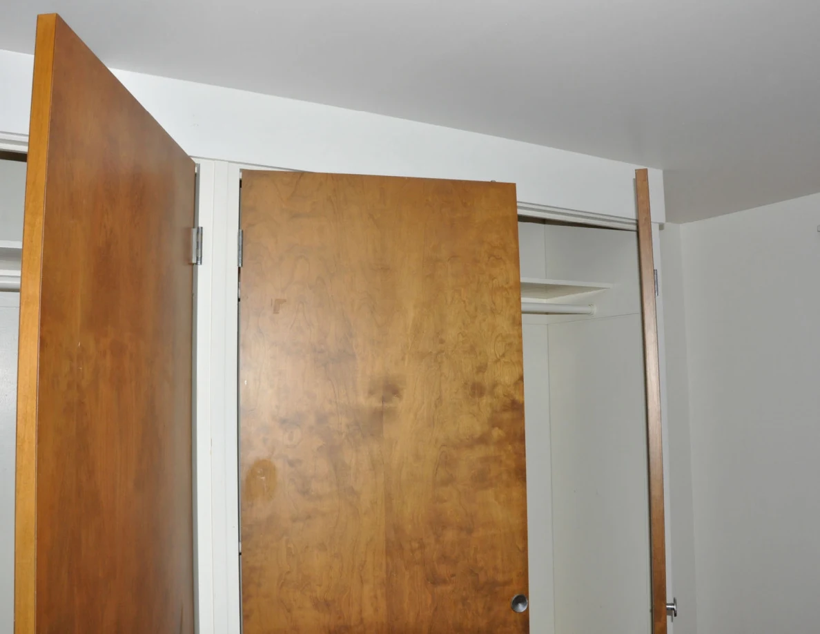 Upper wooden closet doors and white shelving.