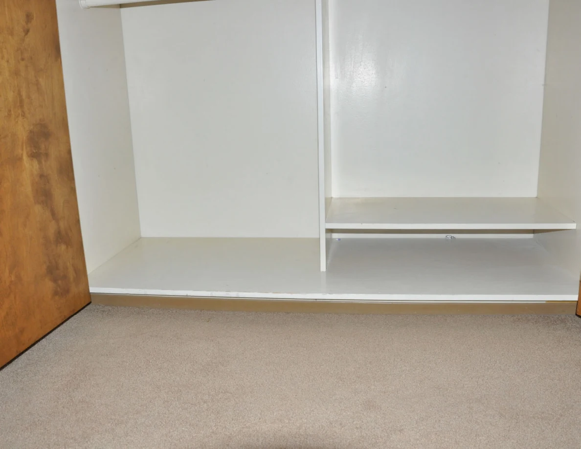 Empty lower closet compartments with a low shelf on the right.