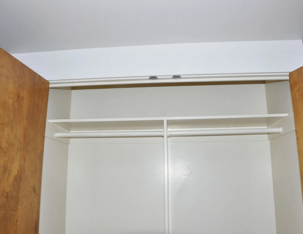 Upper empty closet shelf and rails beneath a white door track.