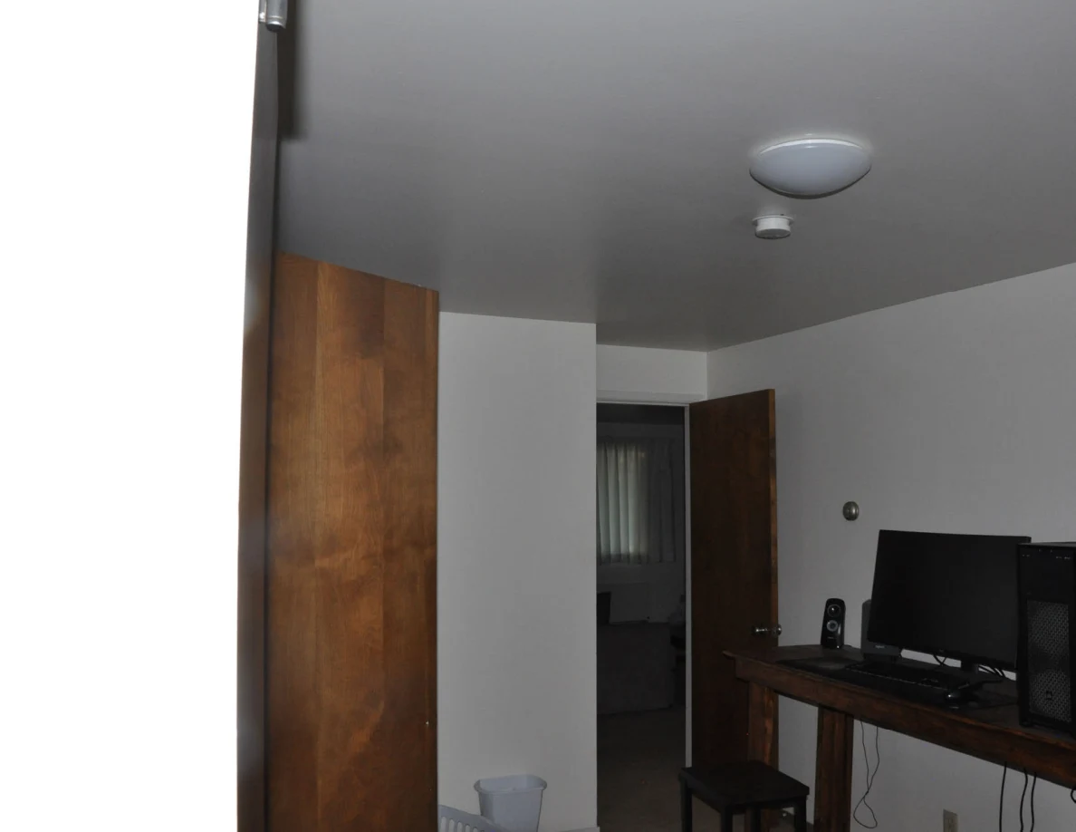 Upper bedroom view with closet, open doorway, computer desk and ceiling light.