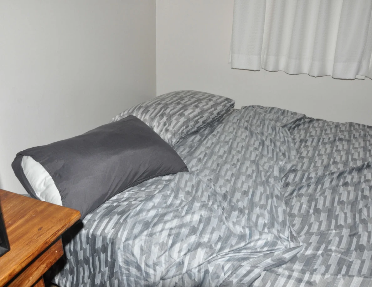 Close view of dark and patterned pillows on a gray-patterned bedspread.
