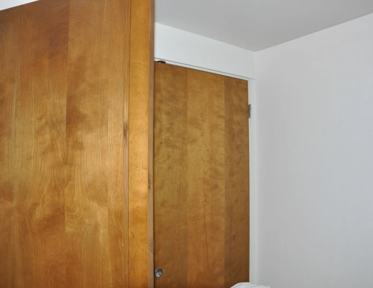 Upper wooden closet doors beside a plain wall.