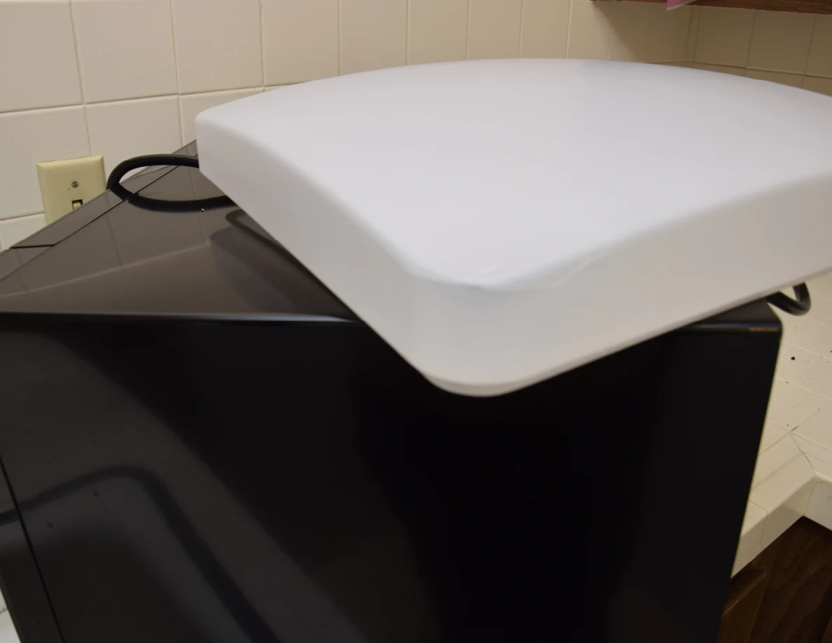 Close view of a white curved rectangular light cover on a black appliance.