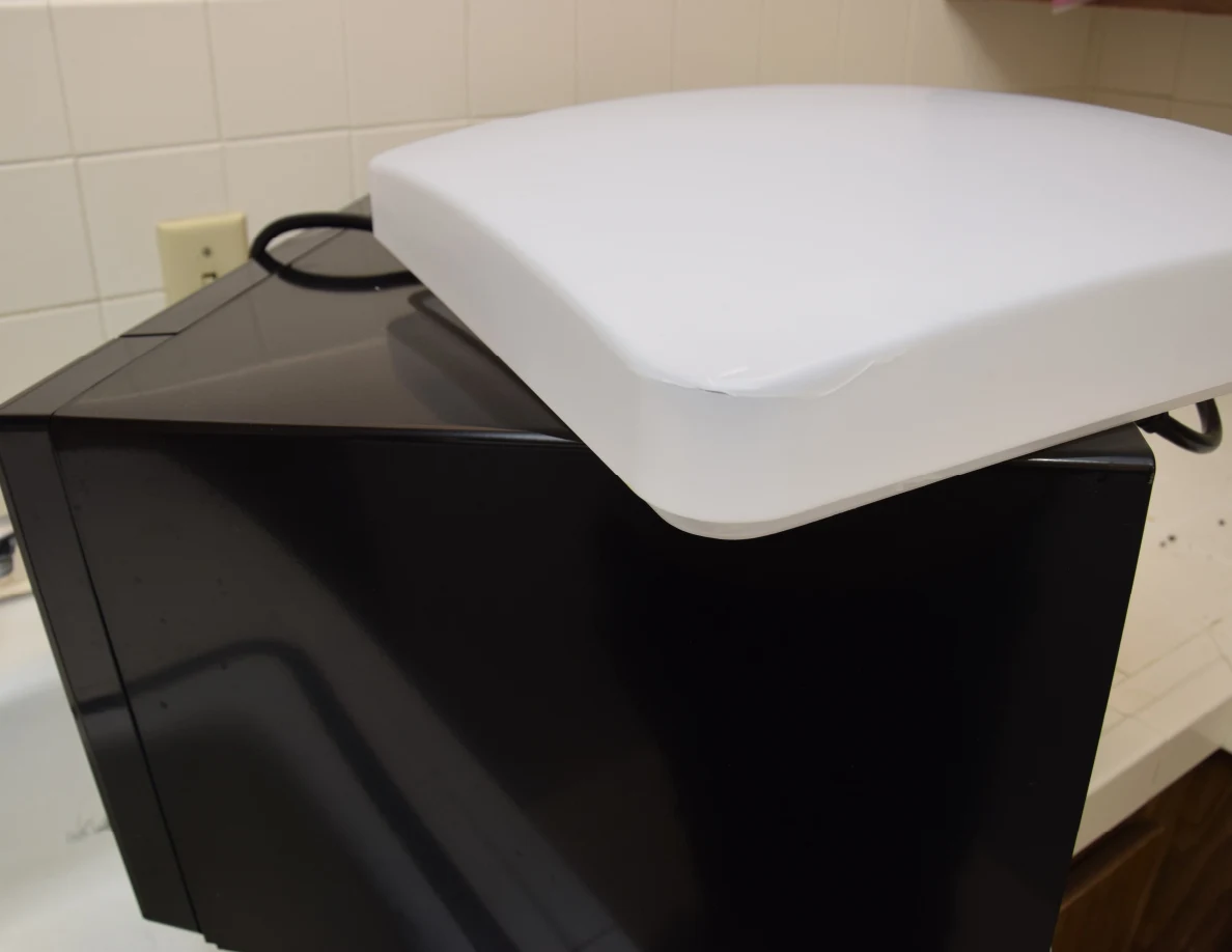White light cover on a black appliance against a tiled kitchen backsplash.