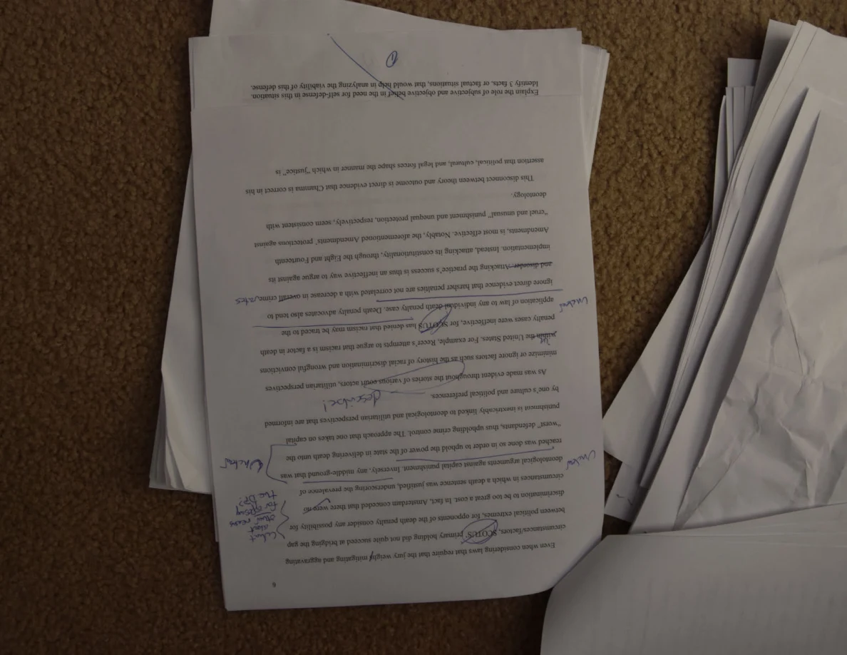 Upside-down essay page with handwritten corrections and notes in the margins.