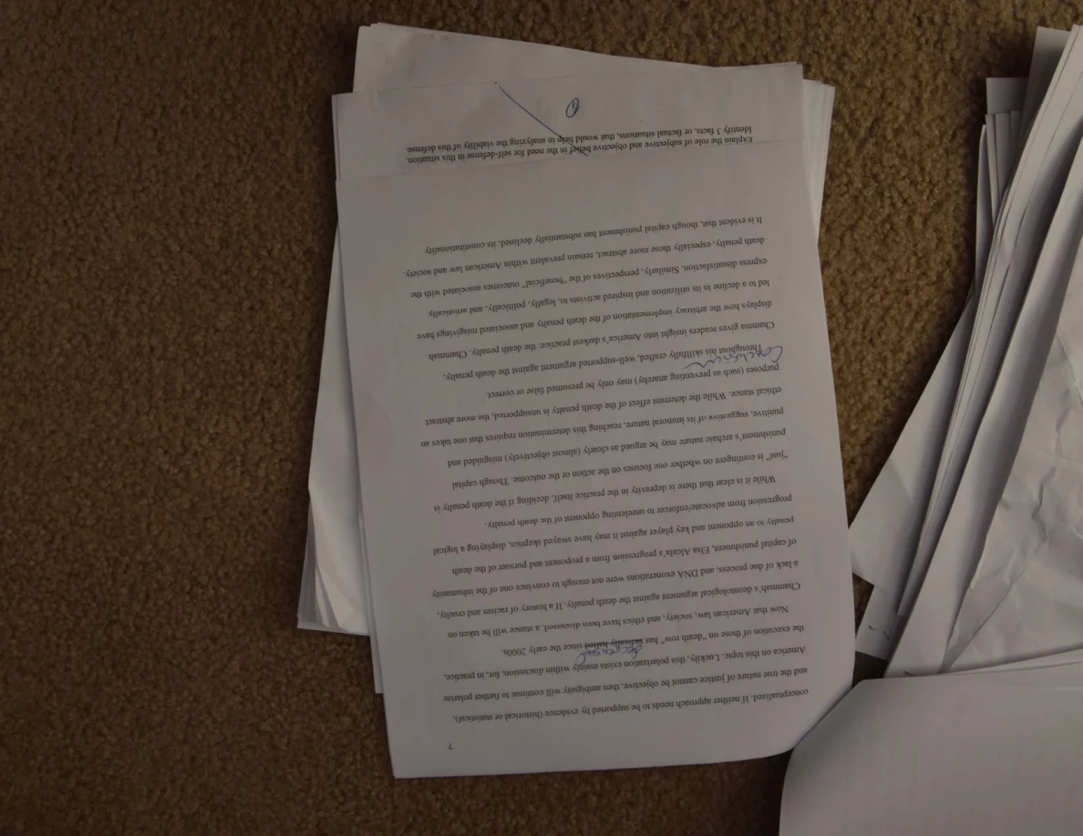 Upside-down printed essay page with underlined passages and handwritten marks.