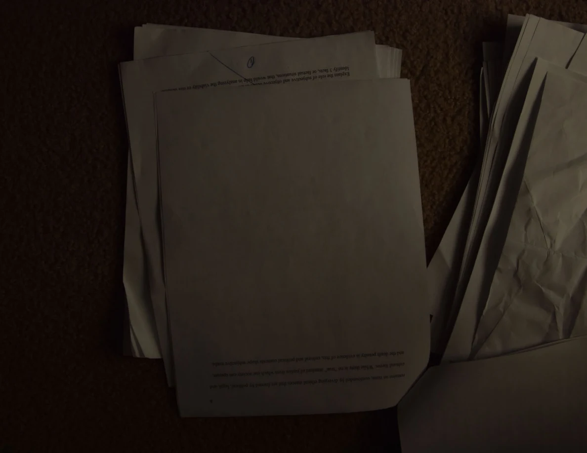 Dim photograph of a mostly blank paper with a few printed lines, lying upside down.