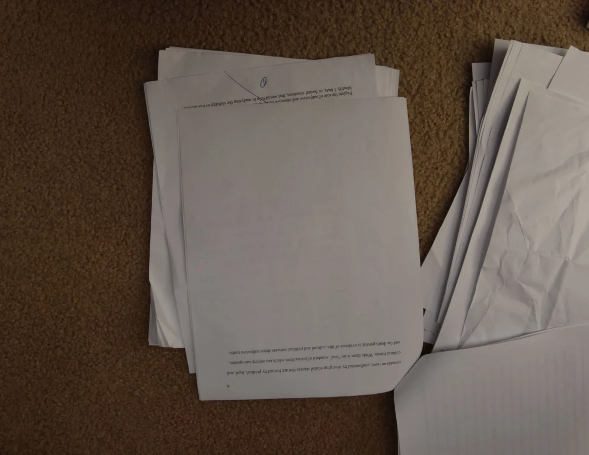 Mostly blank upside-down paper with a few lines of print near one edge.