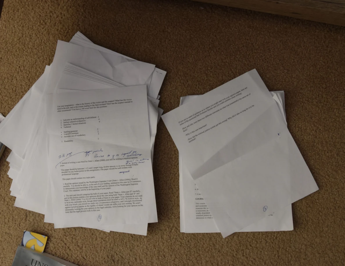 Two stacks of printed papers on carpet, one with handwritten feedback on its top sheet.