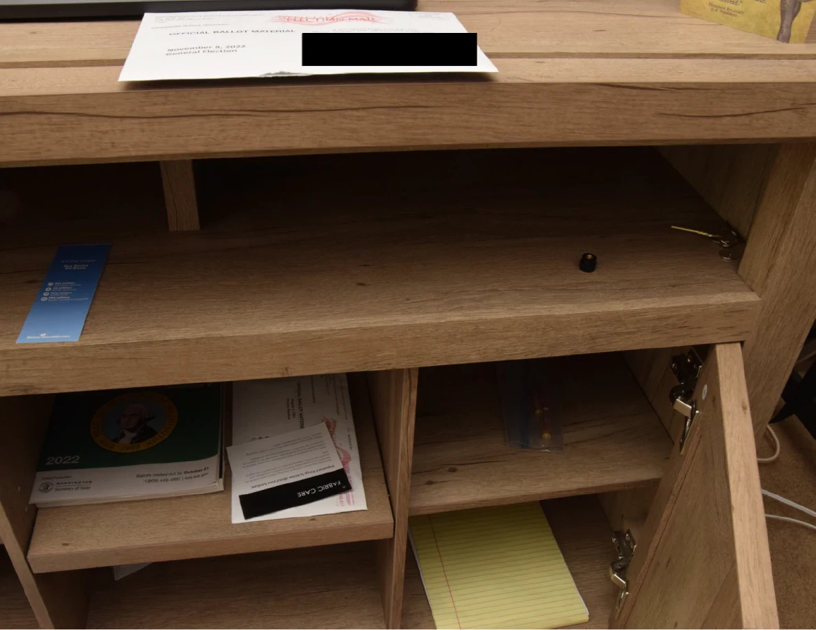 Open television cabinet with books, papers and a yellow notepad; address details are blacked out.