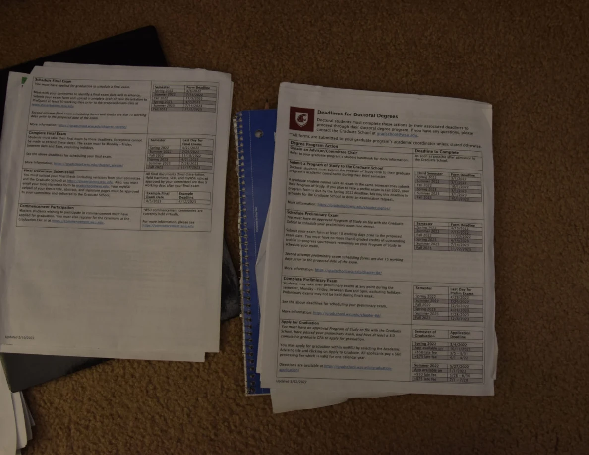 Academic handouts with colored headings and tables on two paper stacks.