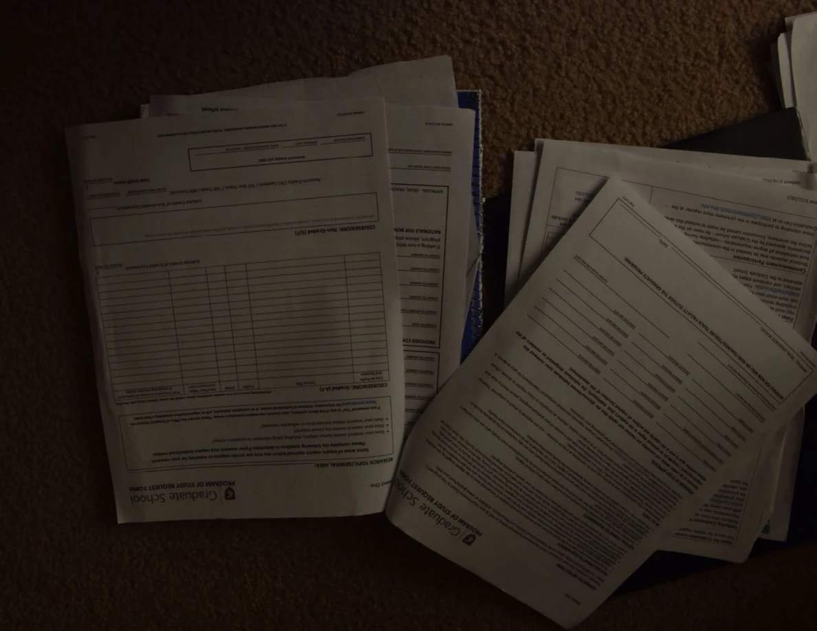 Dim view of academic forms with tables on two paper stacks.