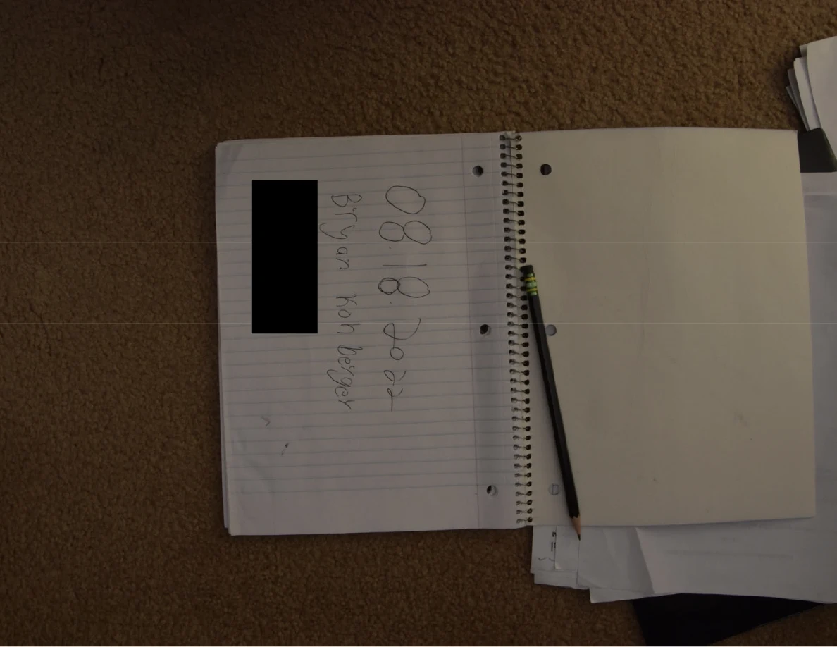 Open spiral notebook with a pencil along its binding and a blacked-out handwritten line.