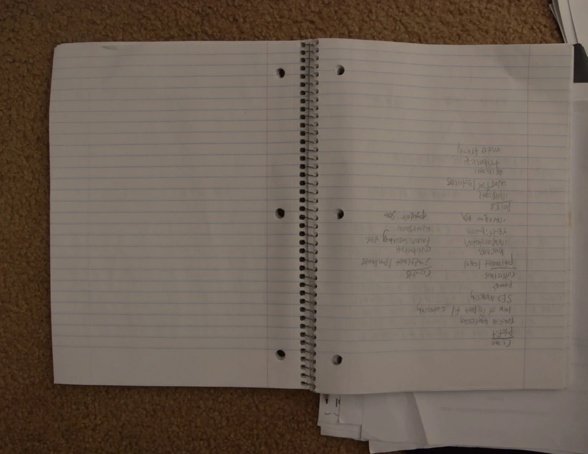 Open notebook with faint handwritten notes on its right-hand page.
