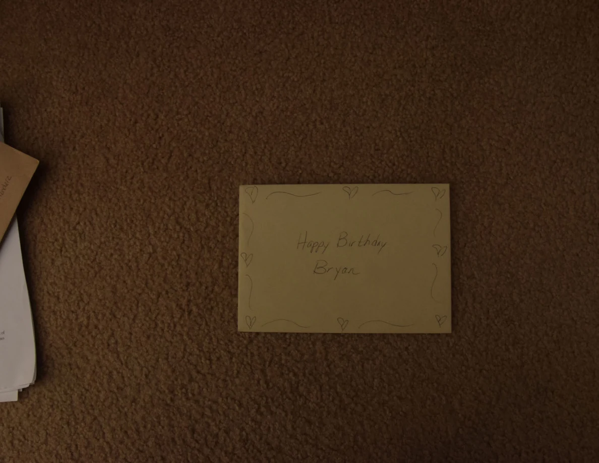 Yellow handwritten birthday card with a decorative border on carpet.