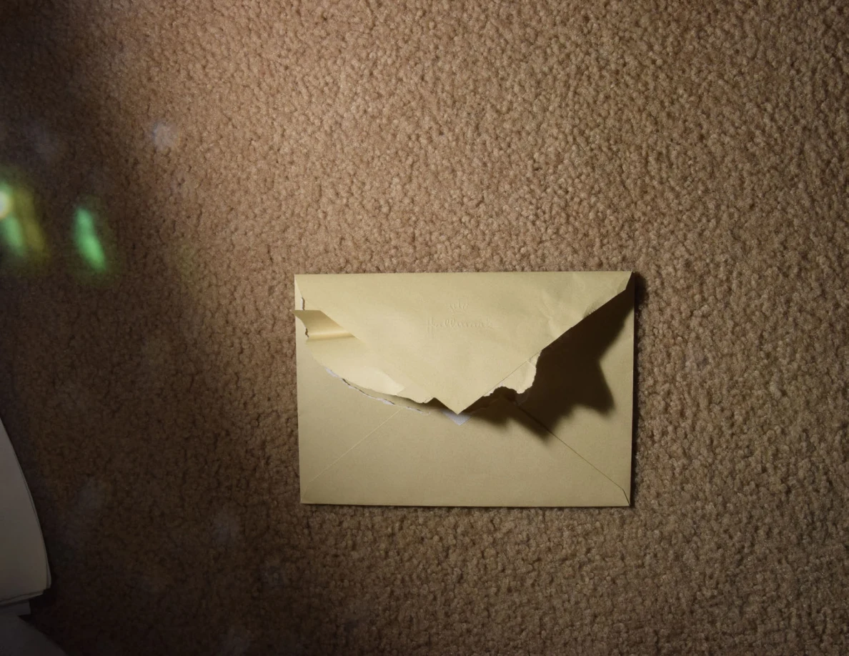 Yellow envelope with a torn flap illuminated by a narrow beam of light.