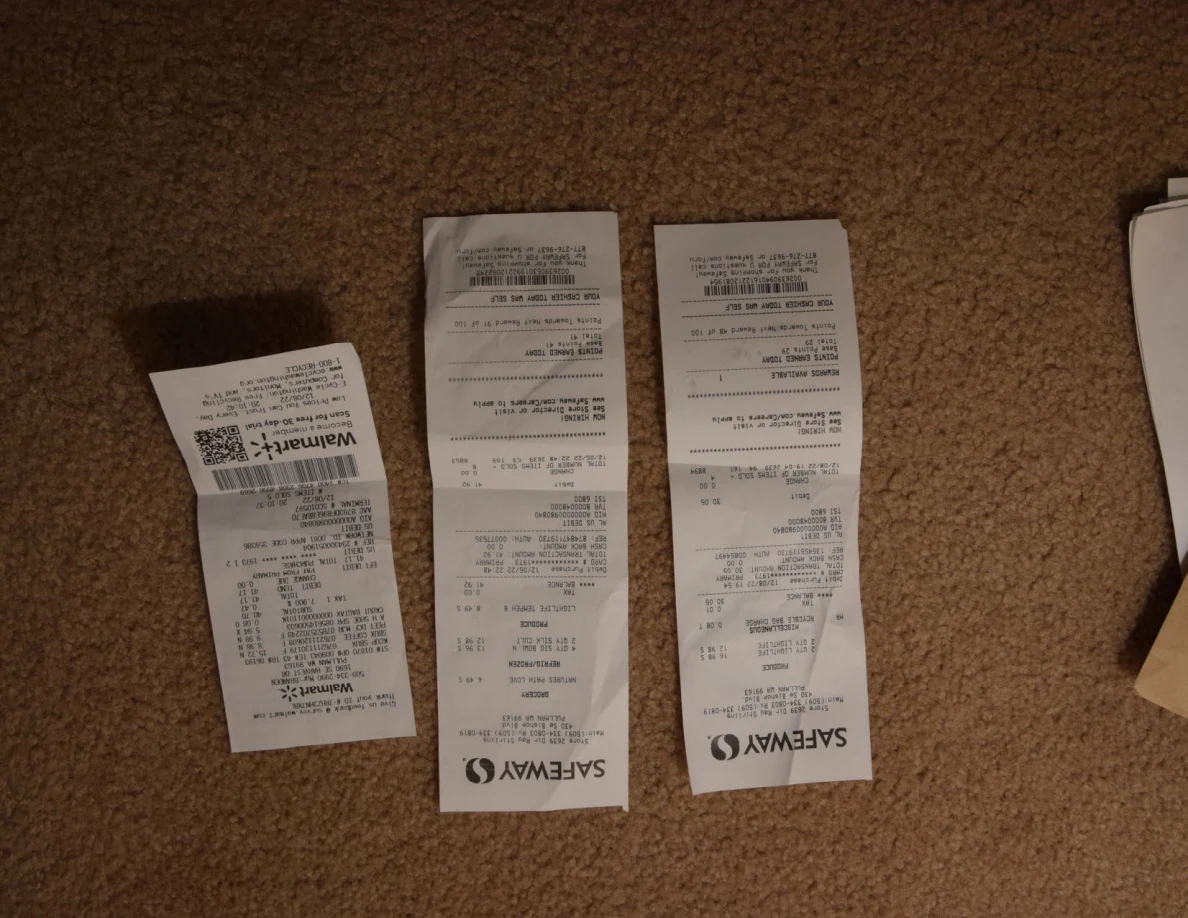 Three shopping receipts, including Walmart and Safeway receipts, arranged on carpet.