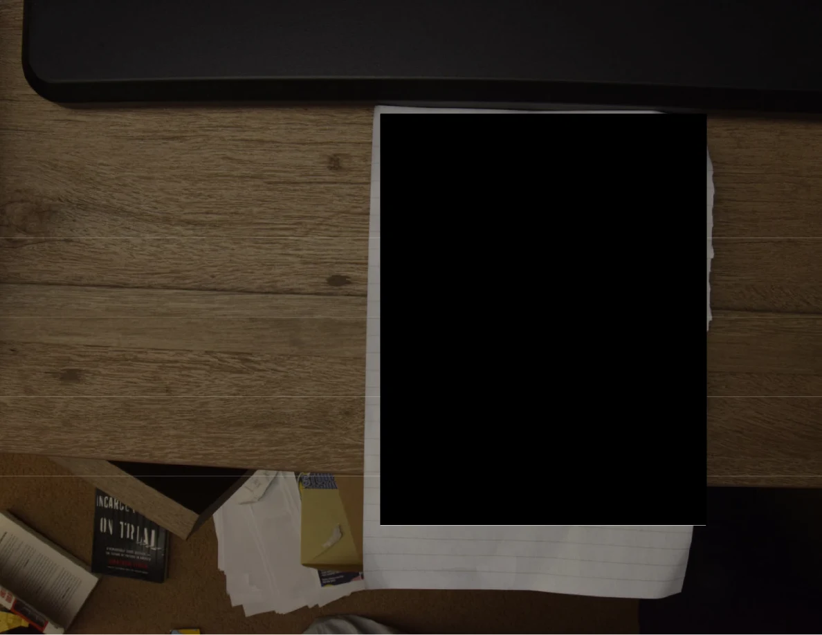 Paper beside a dark rectangular object, with most of the page blacked out.