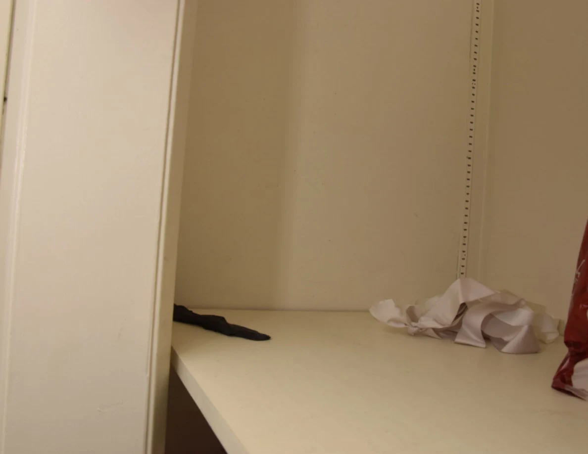 Partly empty closet shelf with crumpled white paper and a dark fabric item.
