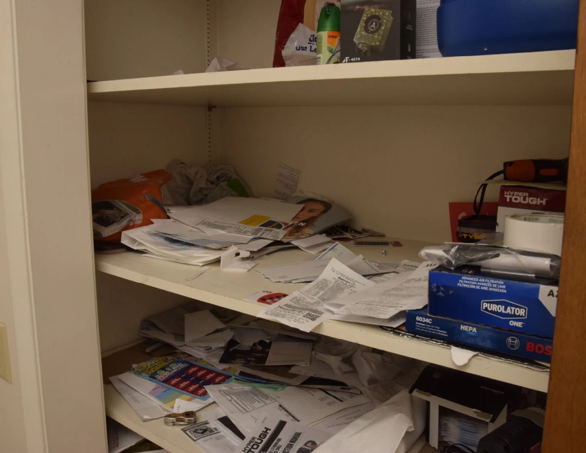 Storage shelves covered with papers, envelopes, packaging and boxed supplies.