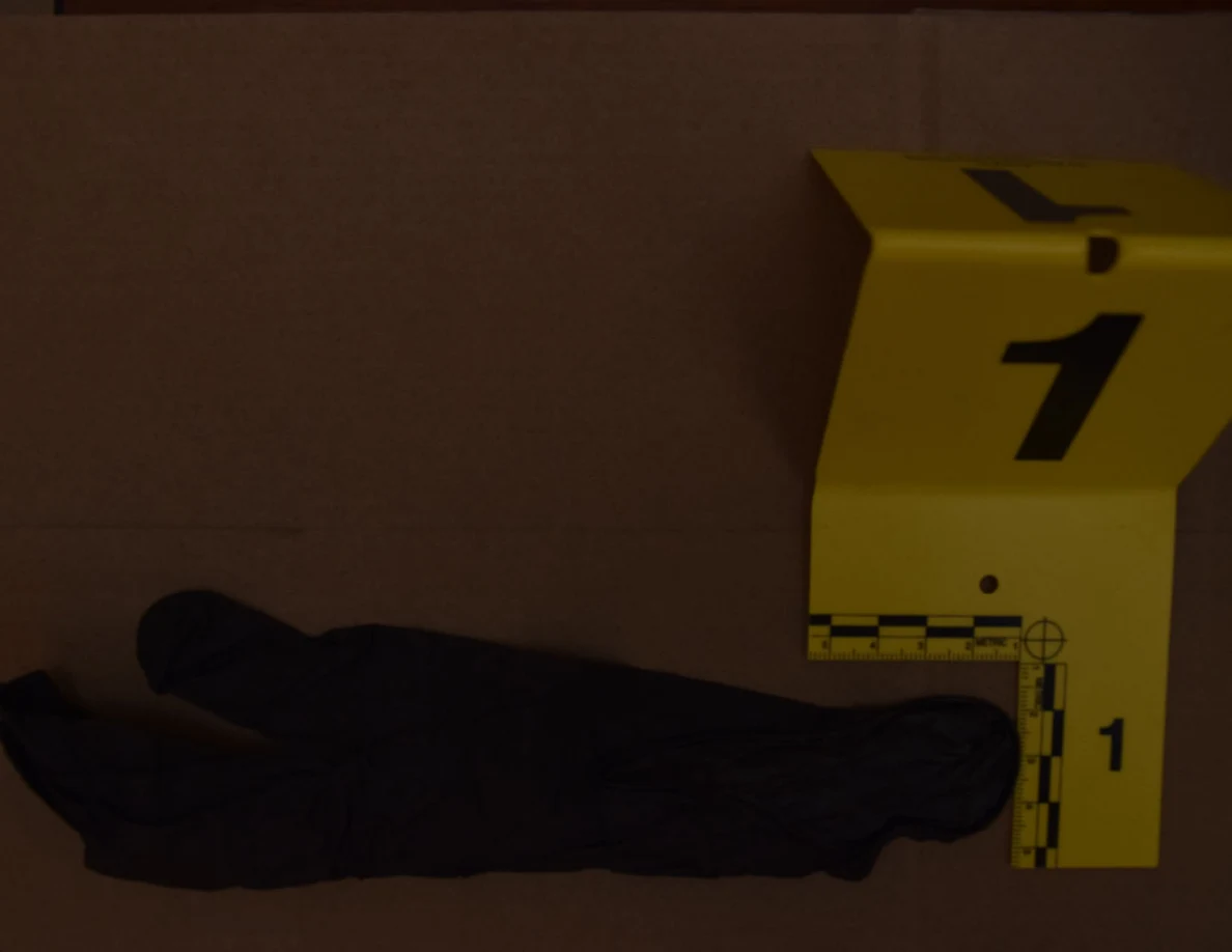 Dim close view of a black glove and yellow measuring marker.