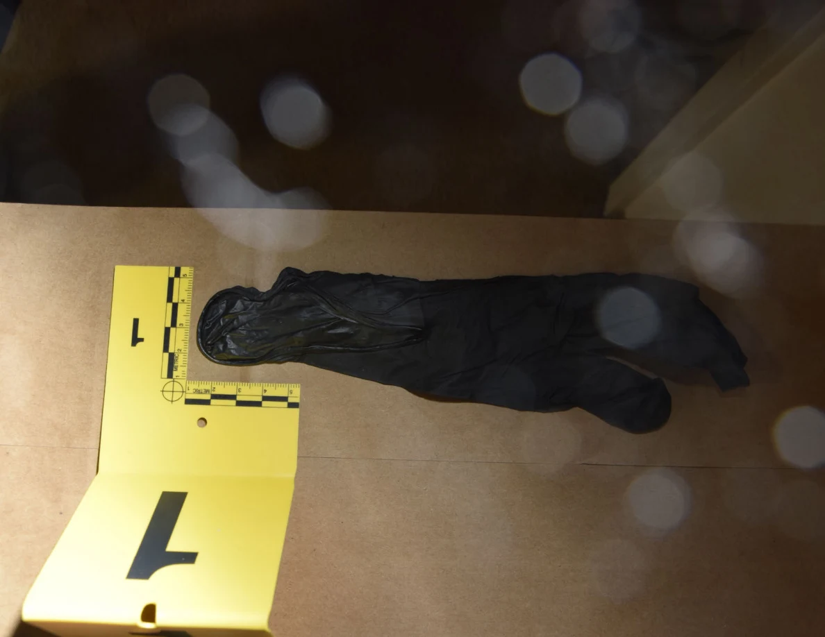Black glove and yellow marker on brown paper, with circular glare spots across the photograph.