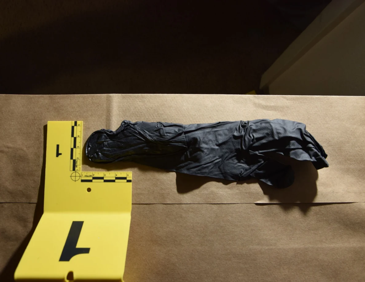 Illuminated black glove beside yellow marker 1 on brown paper.