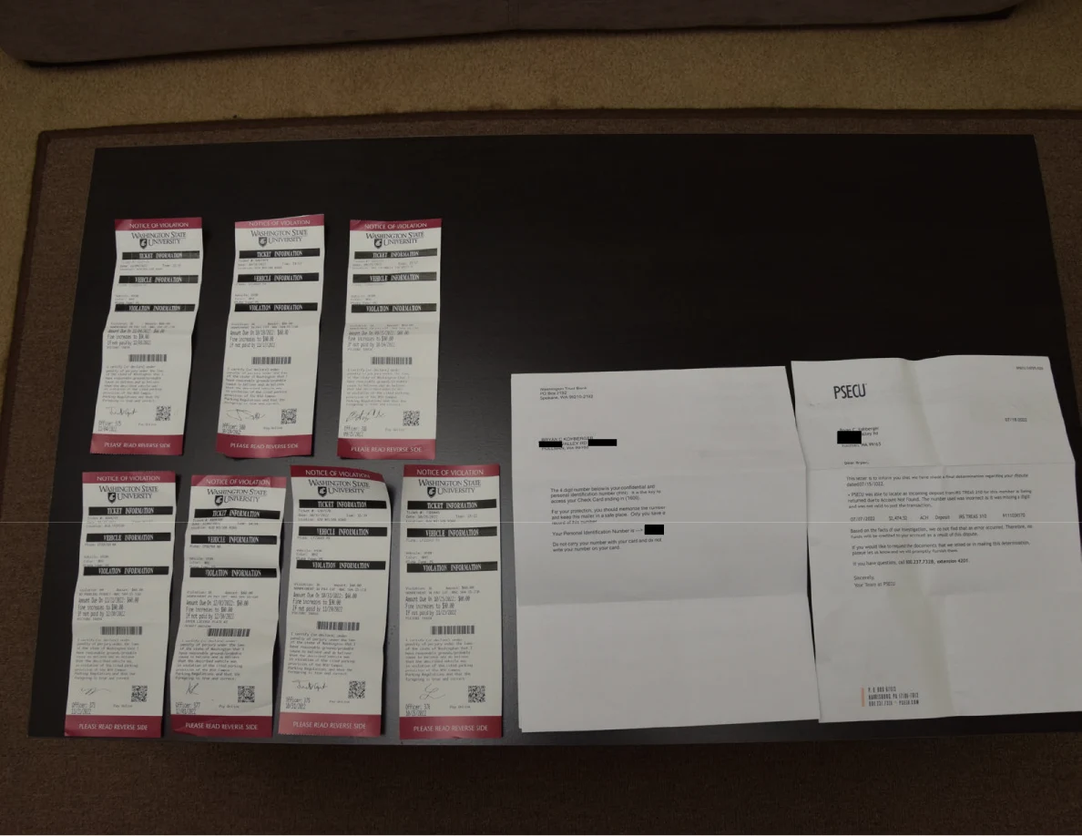 Receipts and two letters arranged on a dark table, with small black redactions.