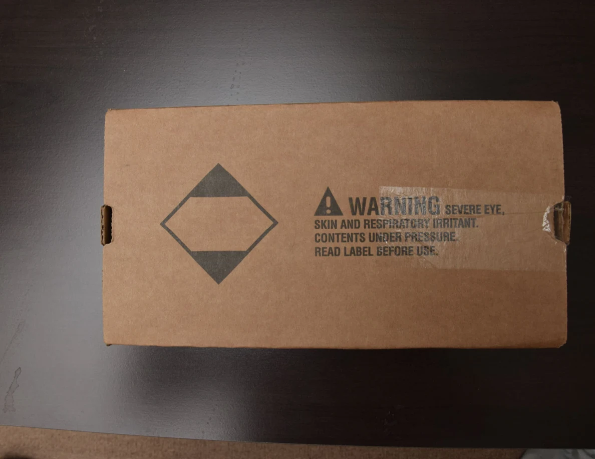 Brown cardboard package with a printed warning and diamond-shaped shipping symbol.
