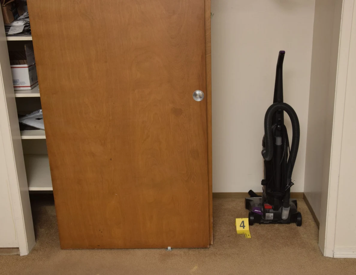 Upright vacuum cleaner beside a wooden closet door and yellow marker 4.