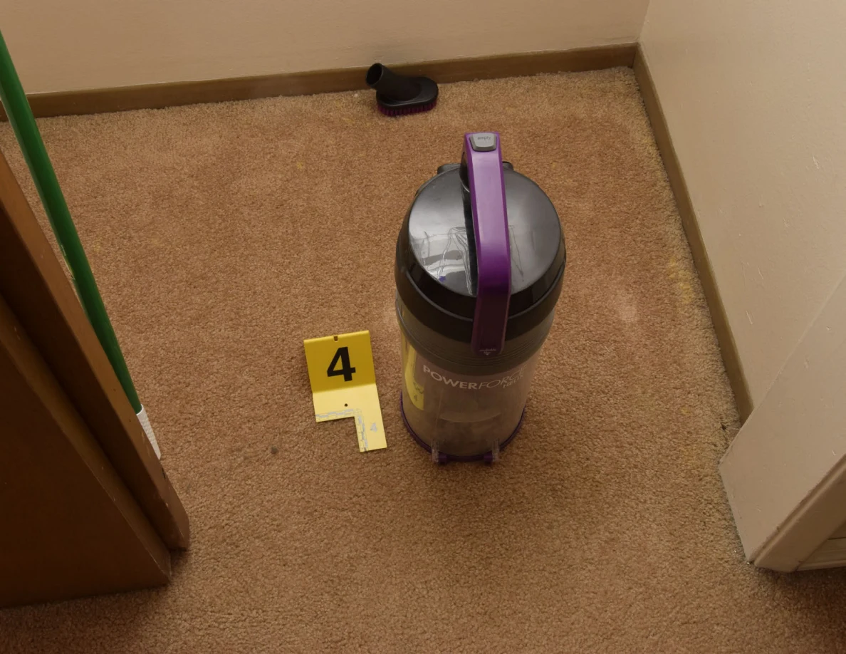 Detached vacuum dust canister on carpet beside yellow marker 4.