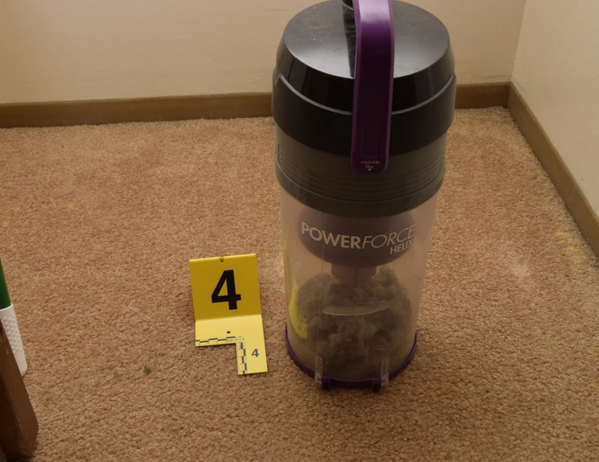 Close view of a transparent vacuum dust canister with purple handle and yellow marker 4.