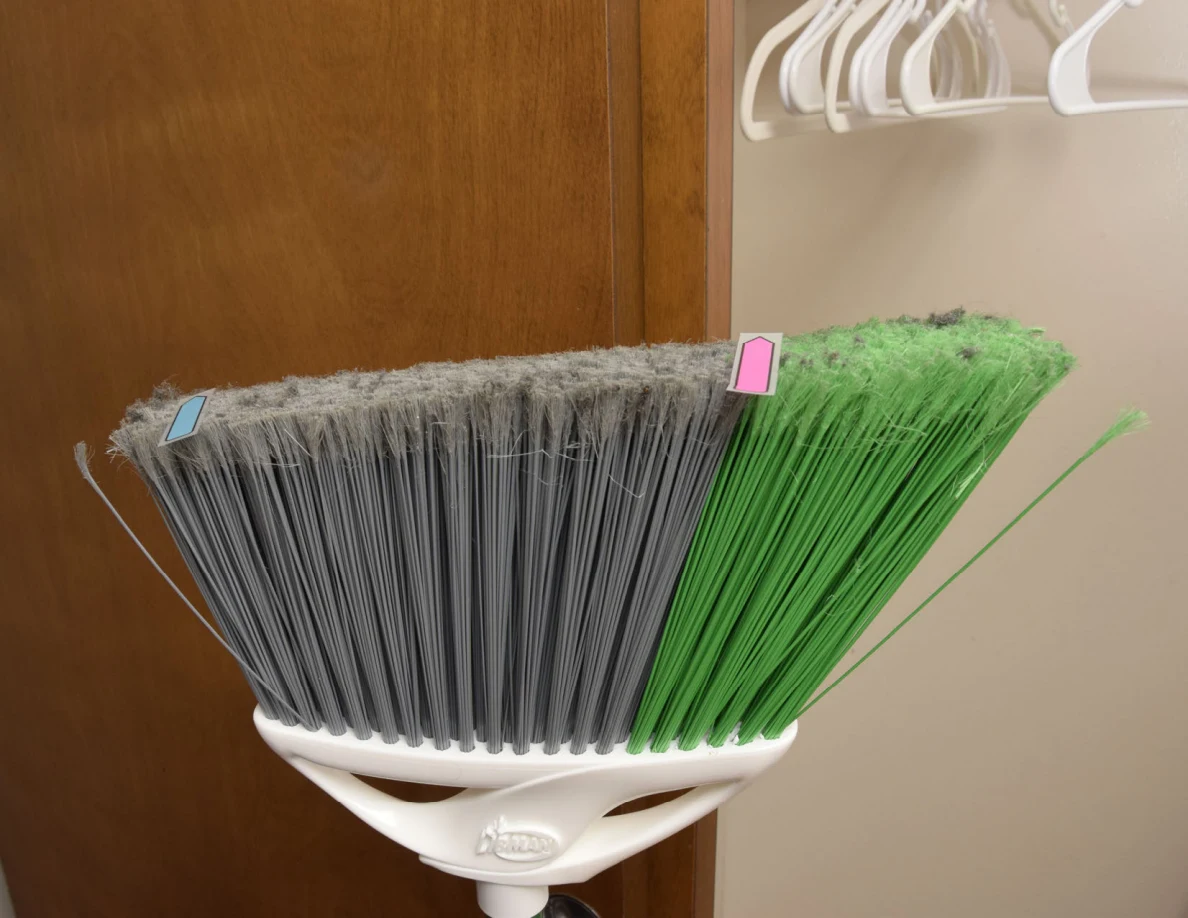 Close view of gray and green broom bristles with small colored tabs near their tips.