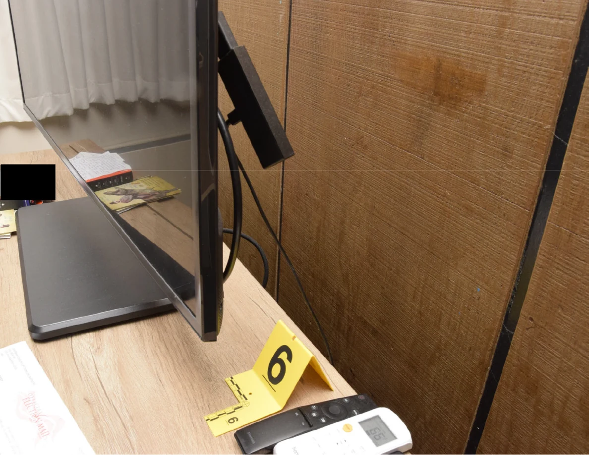Side of a television with remotes and yellow marker 6 on the cabinet.