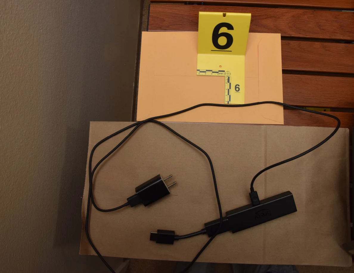 Streaming stick, cables and power adapter on brown paper beside yellow marker 6.