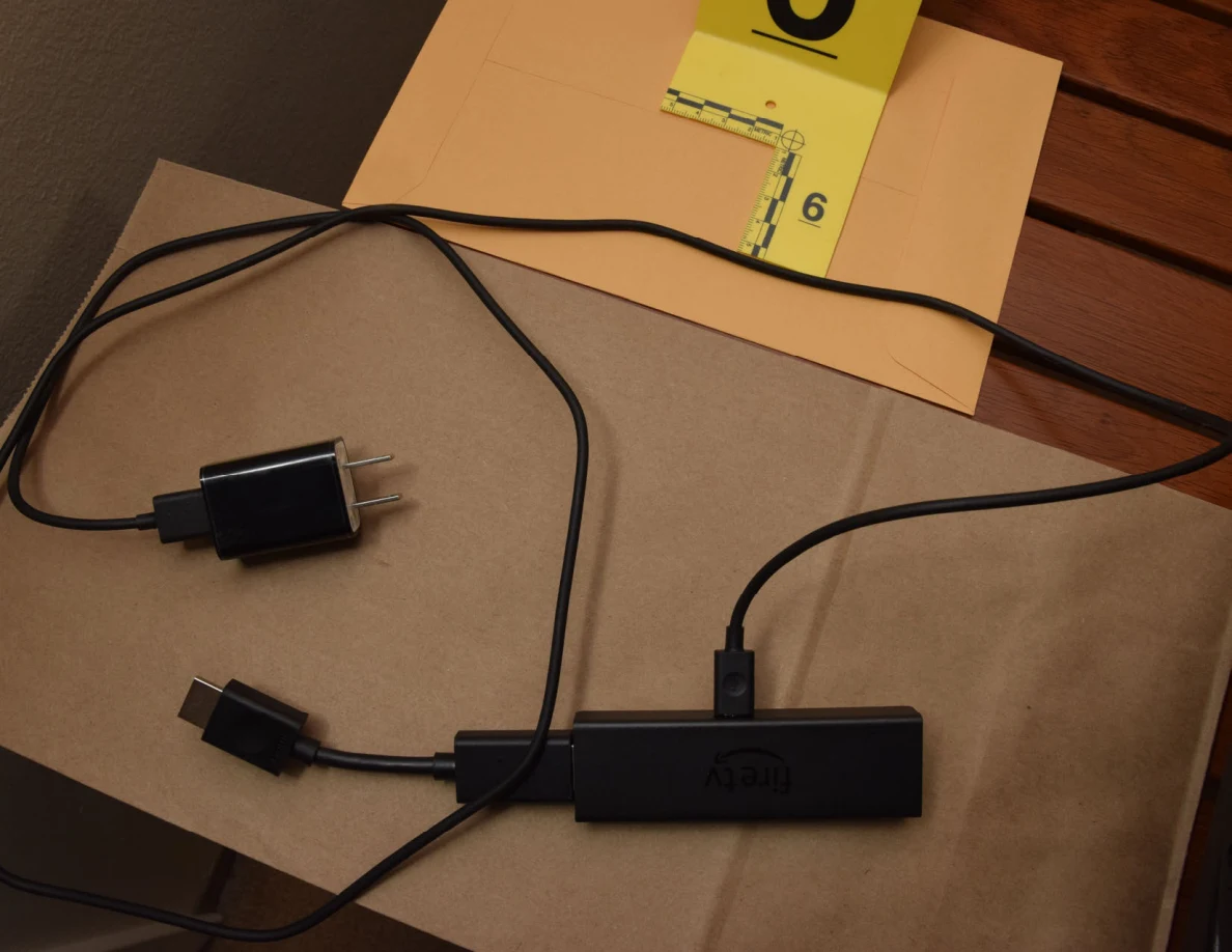 Close view of a streaming stick with HDMI extension cable and power adapter beside marker 6.