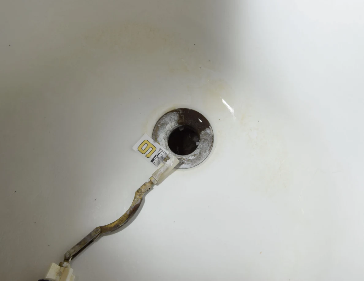 Bathtub drain opening and detached linkage with a numbered scale.