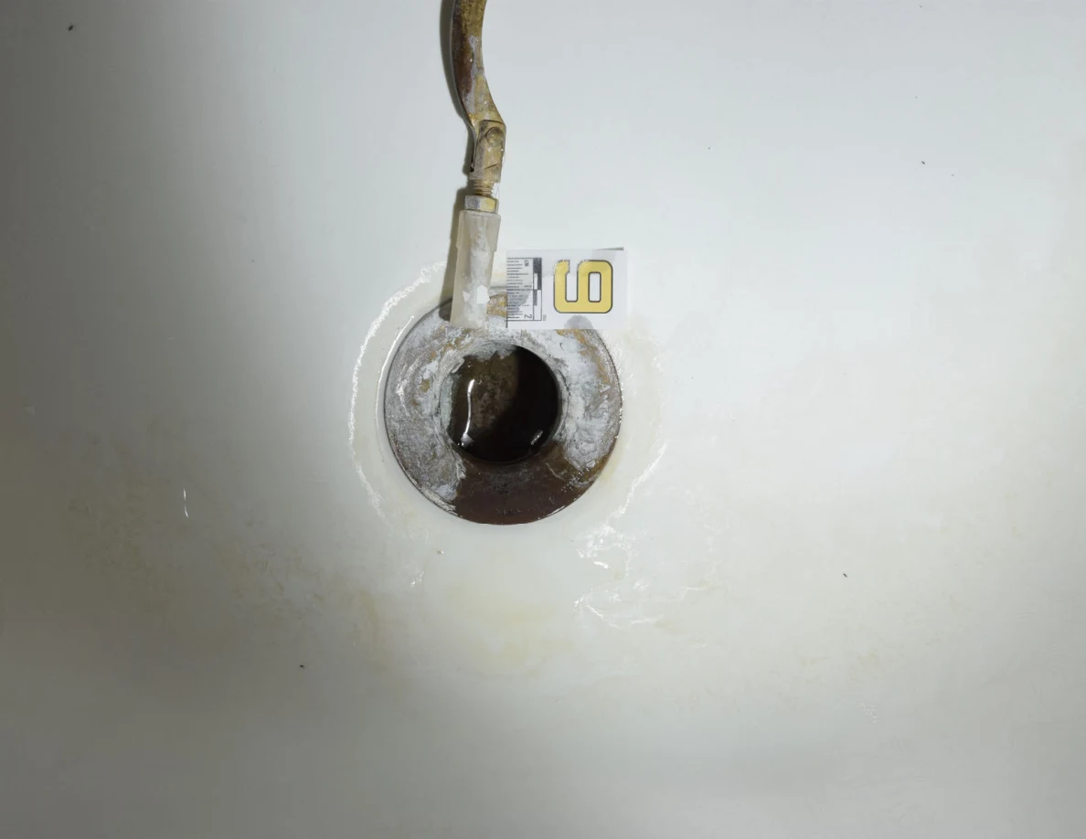 Illuminated drain opening with detached linkage and a small measurement marker.