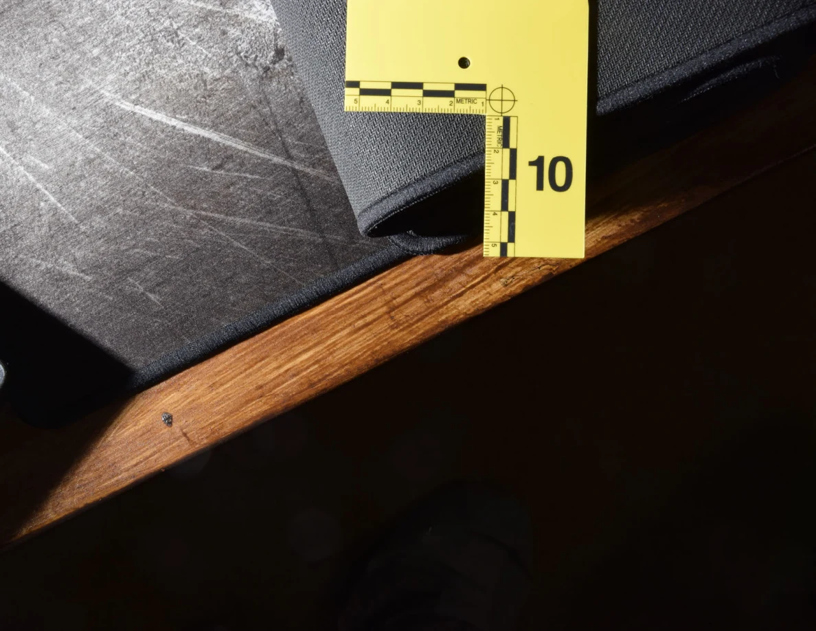 Measuring scale beside the folded edge of a black desk mat on a wooden desk.