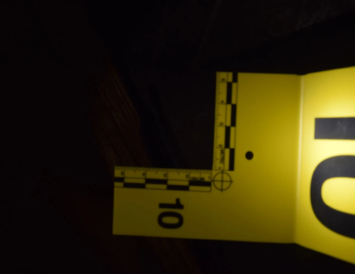 Dark close view of a black mat seam beside a yellow measuring scale.