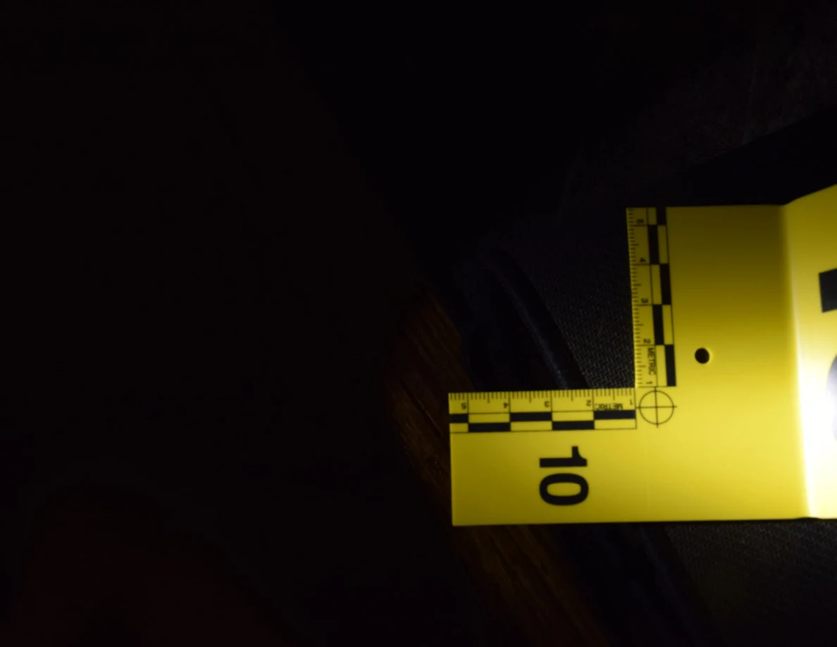 Dark close view of marker 10 and a measuring scale on a black mat.