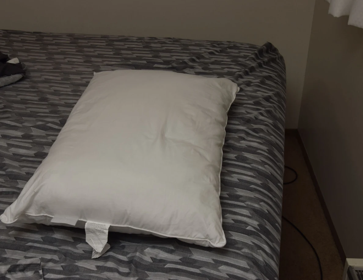 White pillow lying on a gray-patterned bedspread.