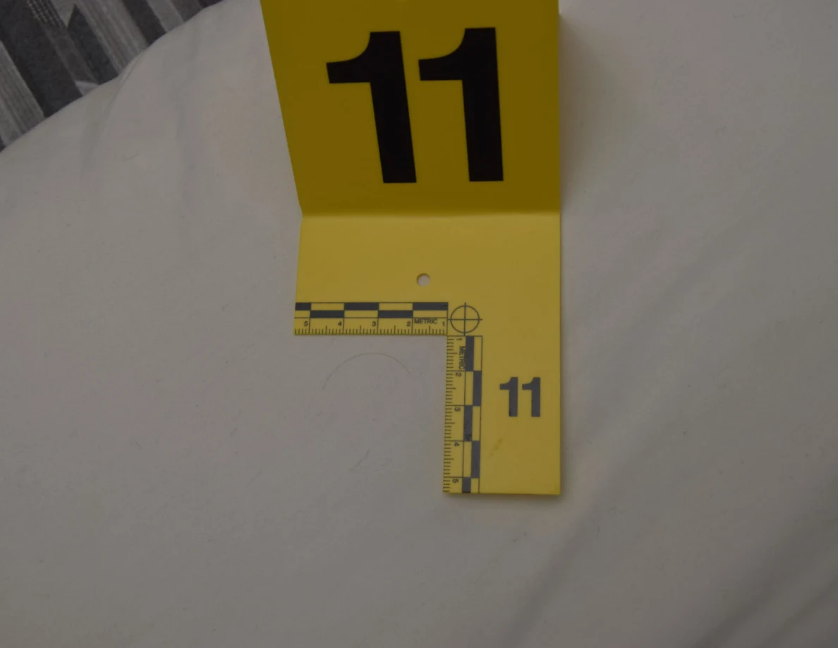 Yellow marker 11 and measuring scale on white pillow fabric.