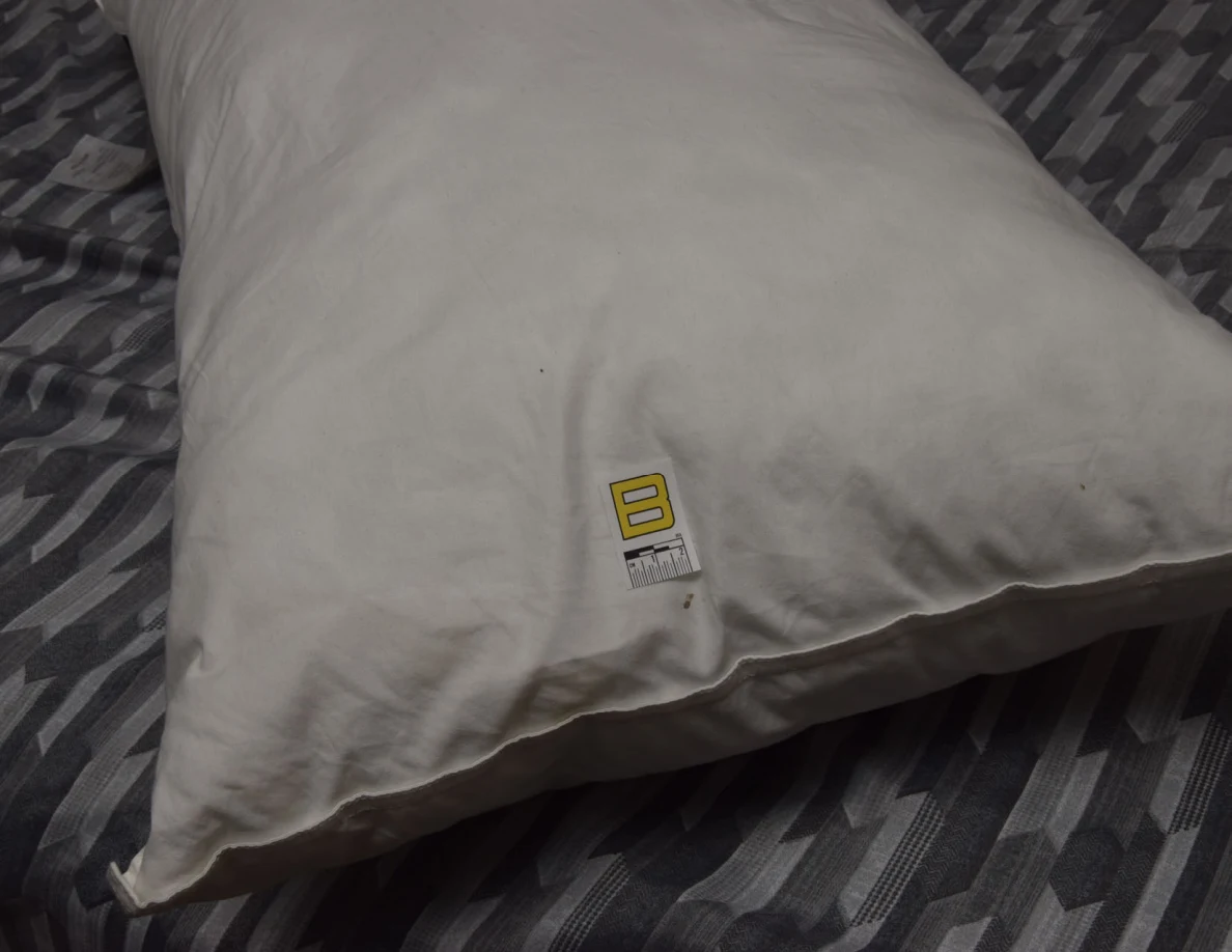White pillow with a small yellow letter B marker near its edge.
