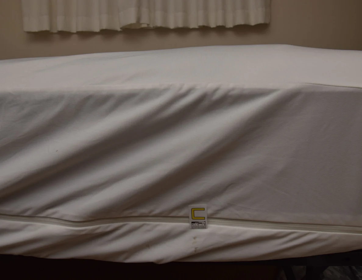 Side of a white mattress cover with a small letter C marker.