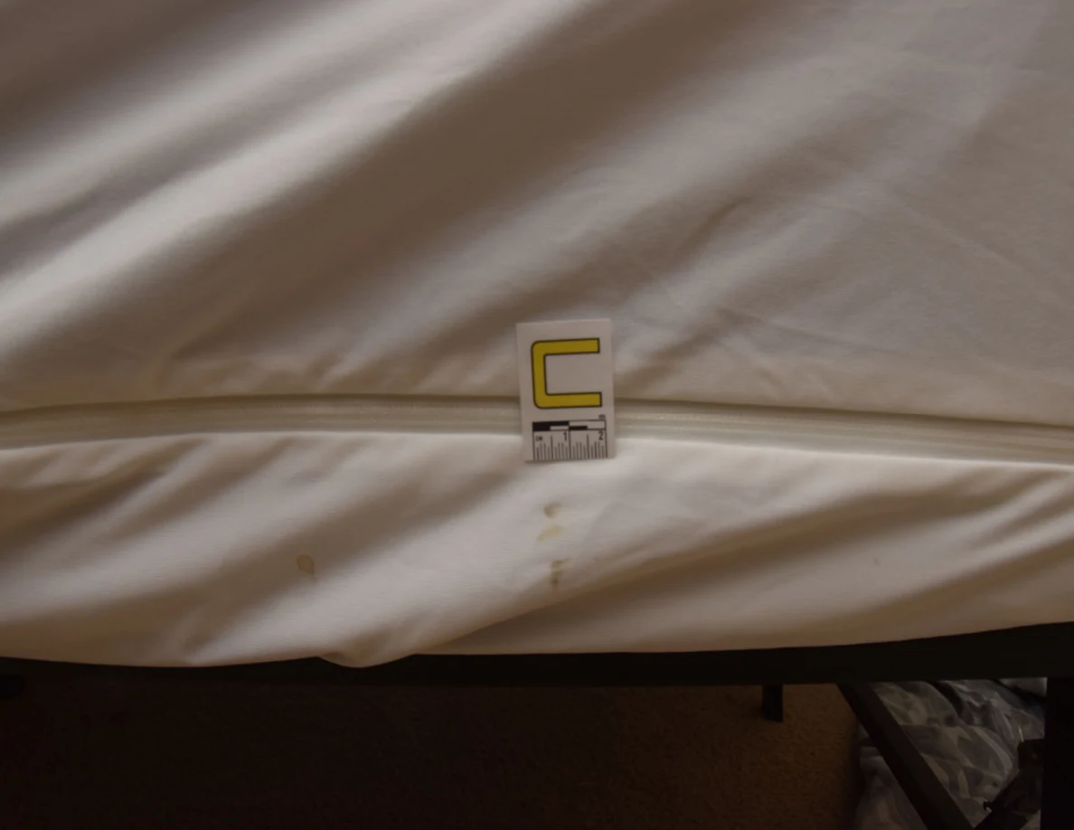 White mattress-cover seam with small tan marks and letter C marker.