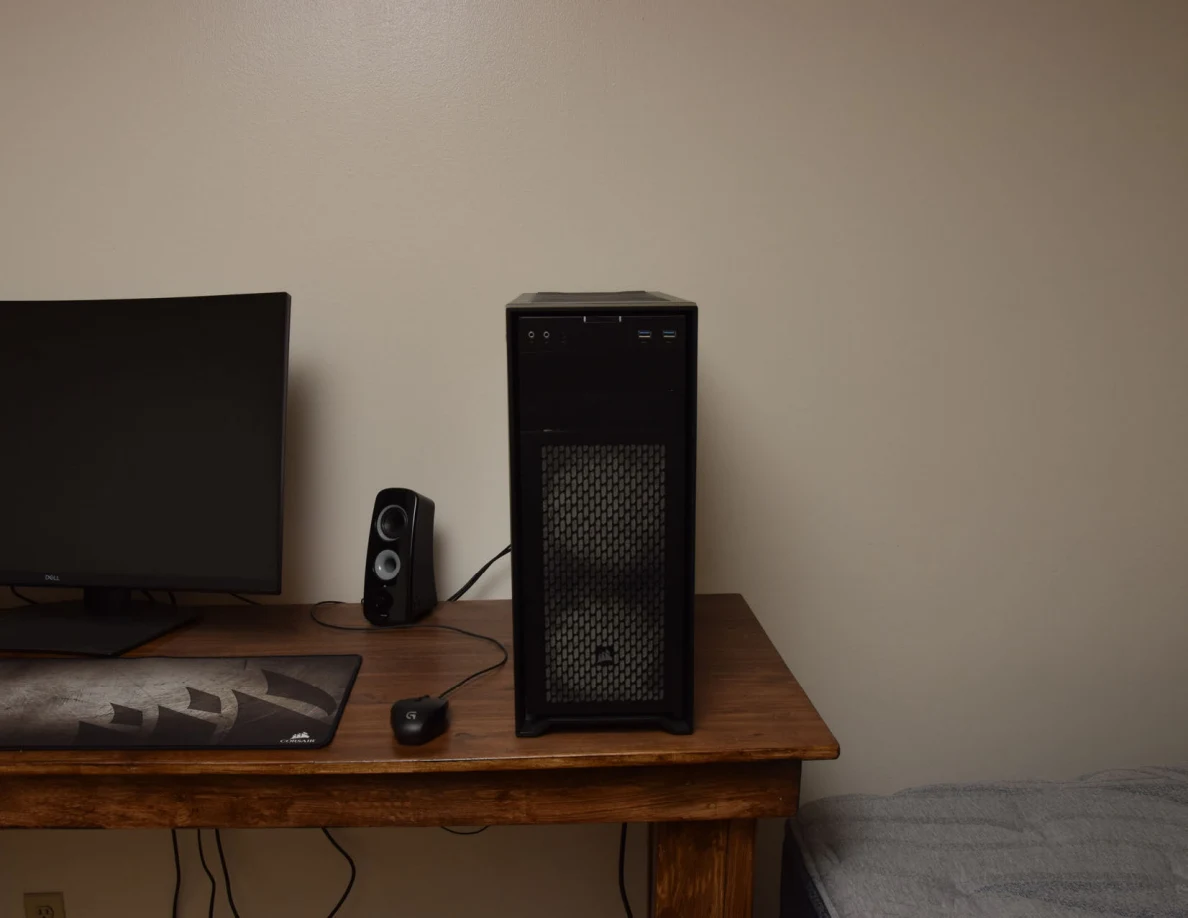 Front of a black computer tower beside monitor, speaker and mouse.